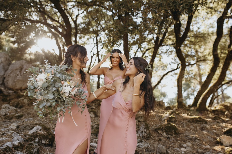 Bridesmaids in blush pink chiffon dresses carrying neutral bouquets